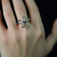 Nahaufnahme eines Rings aus 935 Silber mit geschwungenem Blumen-Design