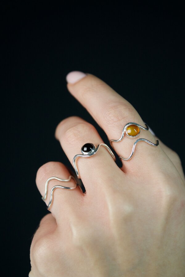 WAVI MOON Ringe Nahaufnahme von geschwungenen Silberringen mit gefasstem Onyx und Bernstein